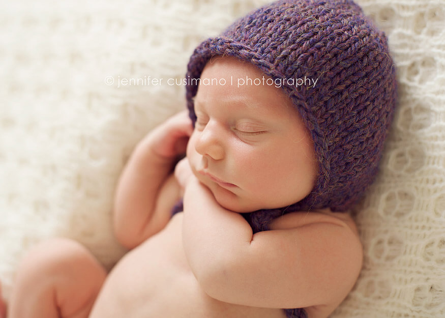newborn baby with a purple bonnet