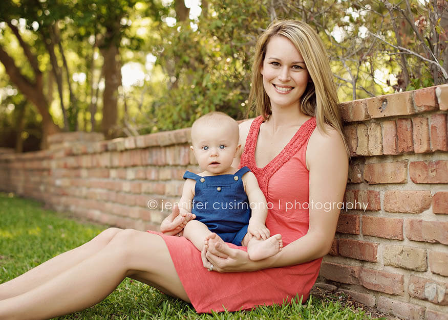 mom holding baby boy leaning against a brick wall in Houston
