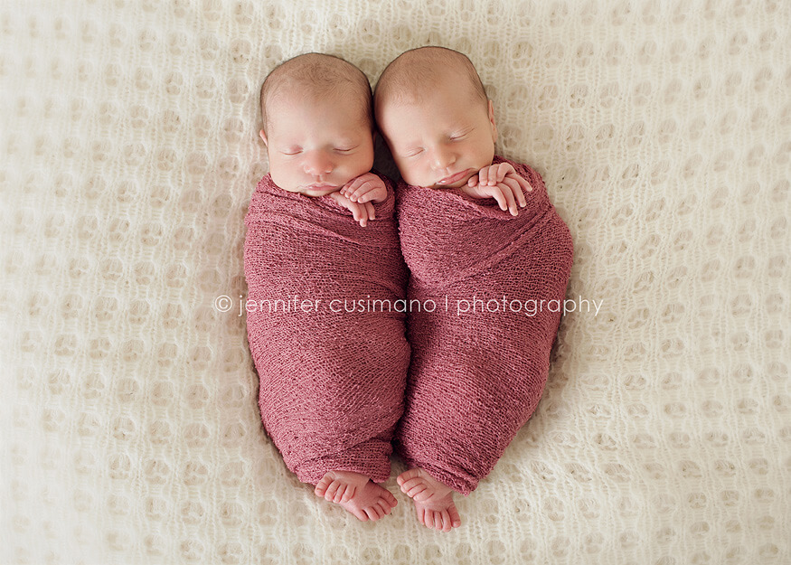 newborn twins swaddled in pink blankets