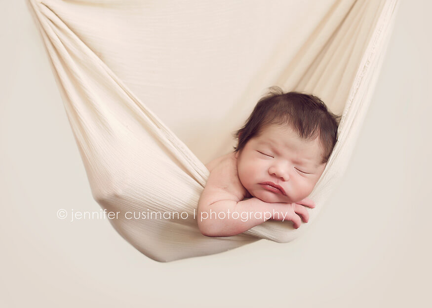 newborn baby boy hanging in a cream sling