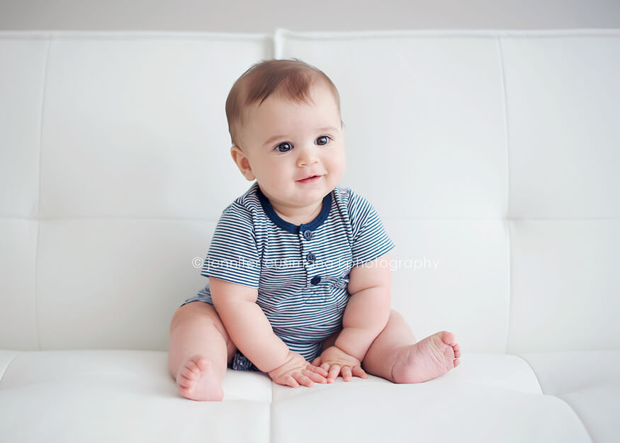 7 month old boy on white couch in navy blue onsie